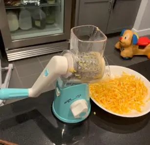 Mandolin Slicer Cheese Shredder Grater Vegetable Slicer Shredding sliced cheese using a mandolin slicer