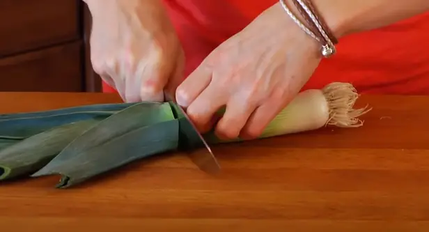 Cut off the top dark green part with knife Cut off the top dark green part of the leek