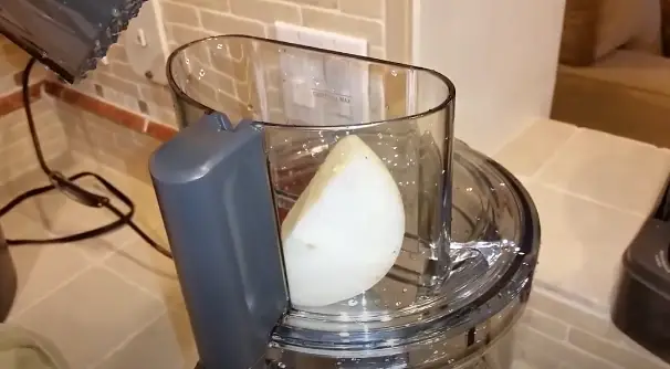 Place the onion pieces into the feed tube of the food processor. Insert the onions