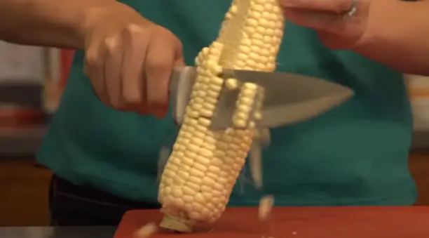 With a sharp knife, make a straight downward cut along one side of the cob Slice off one side