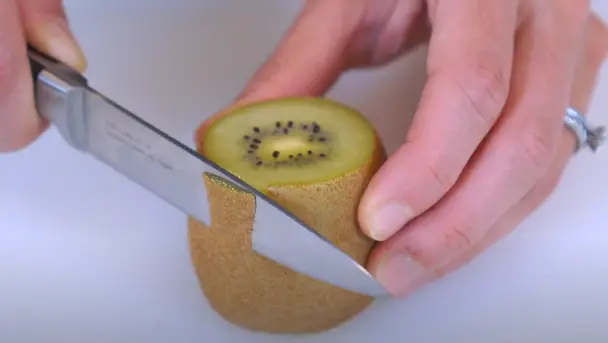Trim a piece of the skin from the kiwi by cutting in a downward motion Trim a piece of the skin