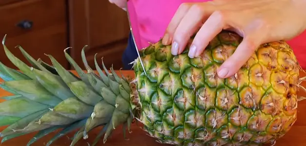 Using a sharp knife, cut off the top and the bottom of the pineapple Using a sharp knife
