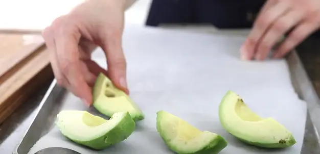 Spread out the avocado pieces on a tray that is lined with parchment paper Spread out the avocado pieces on a tray